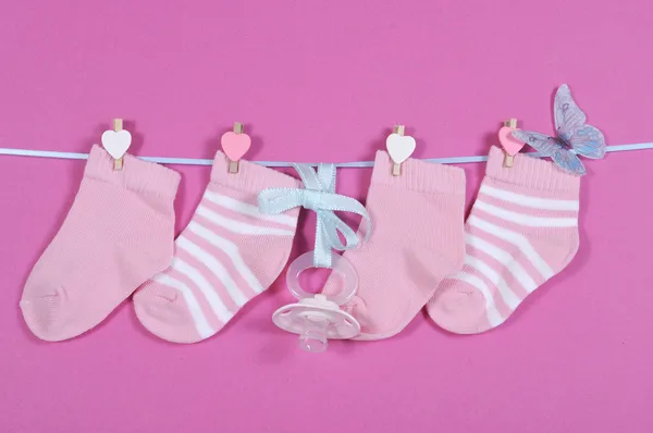 Baby girl nursery socks and dummy pacifier hanging from pegs on — Stock Photo, Image