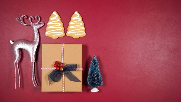 Χριστουγεννιάτικο επίπεδο φόντο με ροζ τάρανδους, δώρο, μπισκότα και δέντρα. — Φωτογραφία Αρχείου