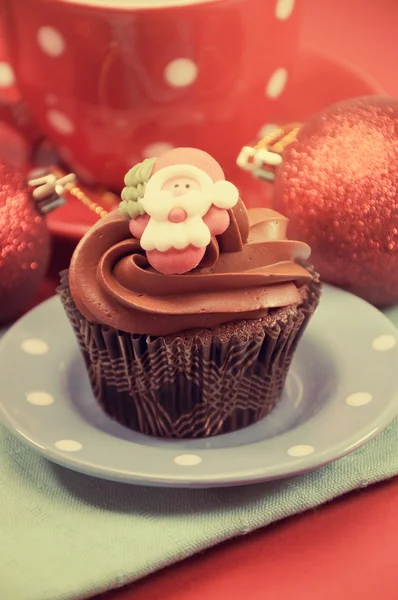 Christmas chocolate cupcakes with Santa faces against a red fest