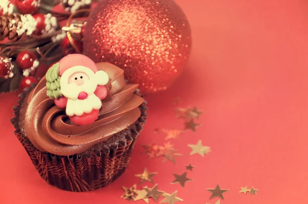 Cupcakes de chocolate de Natal com rostos de Papai Noel contra um festival vermelho — Fotografia de Stock