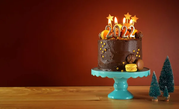 Szczęśliwego Nowego Roku 2022 ciasto czekoladowe ozdobione złotem płonące świece — Zdjęcie stockowe