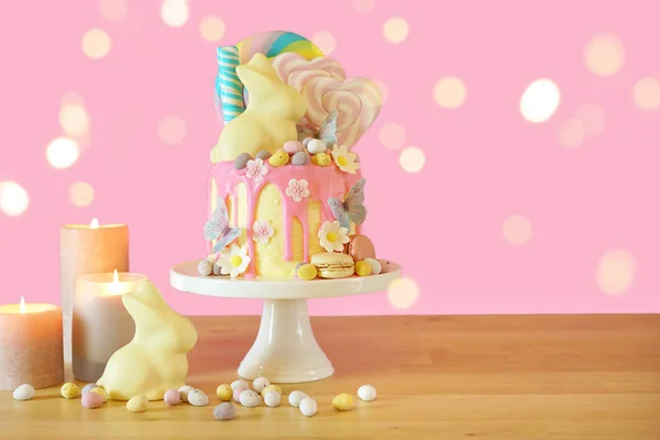 Easter candy land drip cake decorated with lollipops and white bunny. — Stock Photo, Image