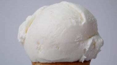 Melting of vanilla tea ice cream on a cone. It flows slowly after the ice cream has melted. On the white background.
