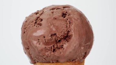 Melting of chocolate ice cream on a cone. It flows slowly after the ice cream has melted. On the white background.