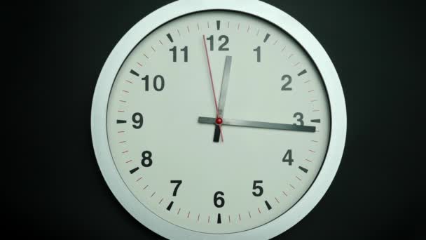 白い壁の時計はゆっくりと時間を示しています 時計の針の動きはゆっくりと過ぎ去った 黒を背景に — ストック動画