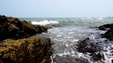Close-up The sea waves gently hit the rocks. On a sunny day.The wind blows gently.