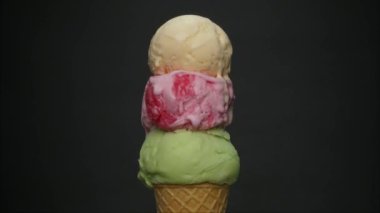 Time lapse, Melting of three flavors of ice cream on a cone. Ice cream water flows from the cone. On the black  background.