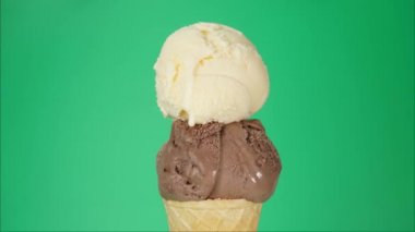 Time lapse, Melting of chocolate and vanilla ice cream on a cone. Ice cream water flows from the cone. On the green background.
