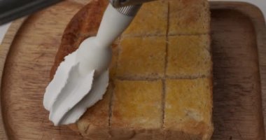 Üst manzara, kızarmış ekmeğin üzerine krema sıkıştır. Tahta tabakta tost..