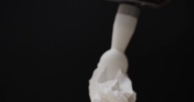 Krem şantiyi sarmal dalgalara sıkıştır. Siyah arka planda pürüzsüz krema.