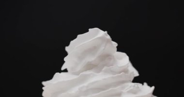 Krem şantiyi spiral bir dalgaya sıkıştır. Siyah arka planda krem şanti. Yakınlaştır, yemek kavramı..