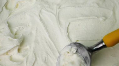 Yavaş çekim kremi sarı bir kaşıkla yaydı. Saf beyaz krema yumuşak ve pürüzsüz.