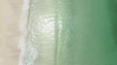 Üst manzara açık deniz suyu ve kumsala vuran yumuşak dalgalar. Güneşli bir günde ve dinlenmek için beyaz kumsalda.