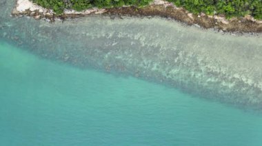 Üst manzara açık deniz suyu denizin altındaki mercanları görebilir. Dalgalar yavaşça kıyıya vurur ve güneş ışığı.