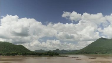 Zaman atlaması bulutların renklerini ve açık gökyüzünü değiştiriyor. Nehirdeki akarsuyun hareketi.