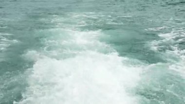 Gemi denizin yüzeyinde yelken açtıktan sonra dalgalar oluştu. Sıcak ve güneşli bir günde deniz sakin ve berrak.