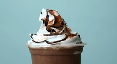 Krem şantiye üzerine çikolata tozu dök. Mavi arkaplan, gıda konsepti.