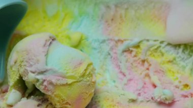 Mavi kaşıkla kaplanmış gökkuşağı dondurması. Dondurma dokusunun desenleri ve renkleri.