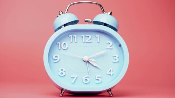 時間の経過は 青い目覚まし時計の時間を教えてください ピンクを背景にした高速時計回りの回転 — ストック動画