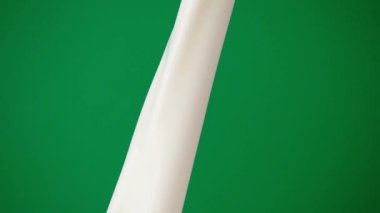 Yumuşak sütü yavaşça dök. Pastörize edilmiş ve yeşil arka planda saf beyaz süt içmeye hazır..