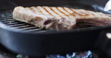 Domuz bifteği tavada kızartılıyor. Bifteğin şablonu ve tava sıcak sobanın üstünde..