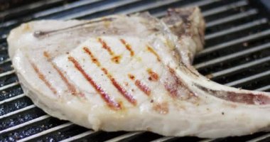 Tavada yakın plan domuz bifteği. Biftek ve tavadaki desen sıcak sobanın üzerinde. Yiyecek konsepti.