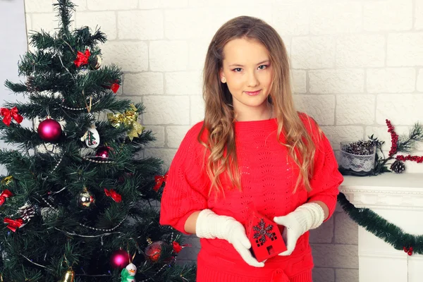 Mladá dívka v červených šatech u vánočního stromu — Stock fotografie