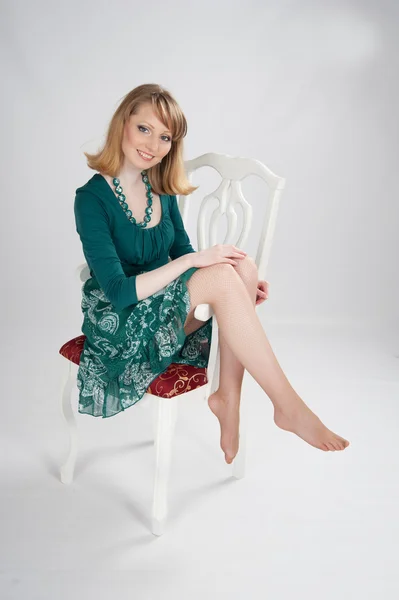 L kobiety w zielonej sukni siedzi na krześle — Zdjęcie stockowe
