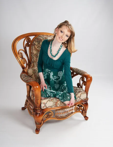 L žena v zelených šatech sedí na židli — Stock fotografie