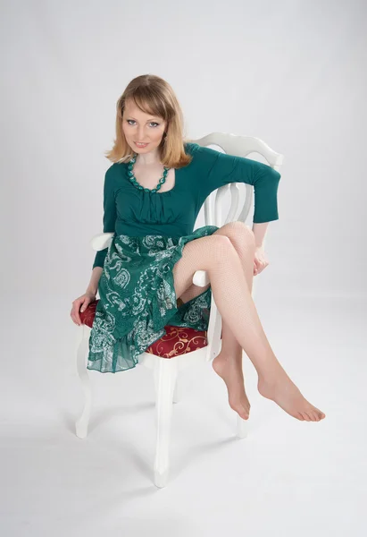 L woman in a green dress sitting on a chair — Stock Photo, Image