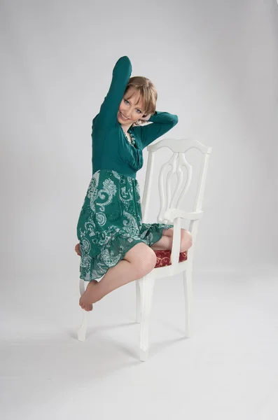 L nő egy zöld ruha ül egy széken — Stock Fotó
