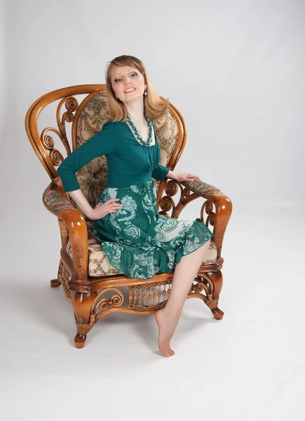 L kvinna i en grön klänning som sitter på en stol — Stockfoto