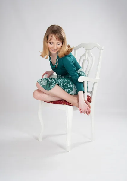 L woman in a green dress sitting on a chair — Stock Photo, Image