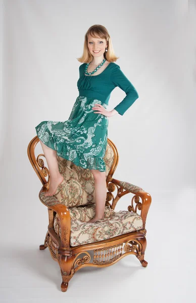 L woman in a green dress sitting on a chair — Stock Photo, Image