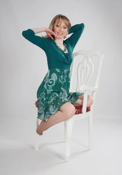 L woman in a green dress sitting on a chair — Stock Photo, Image