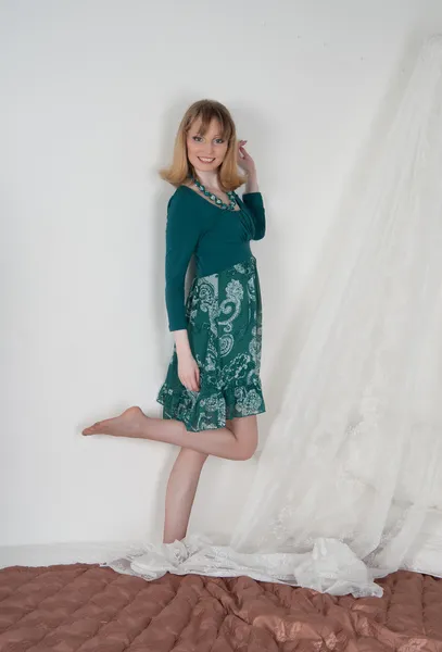 Sexy woman in green dress on the bed — Stock Photo, Image