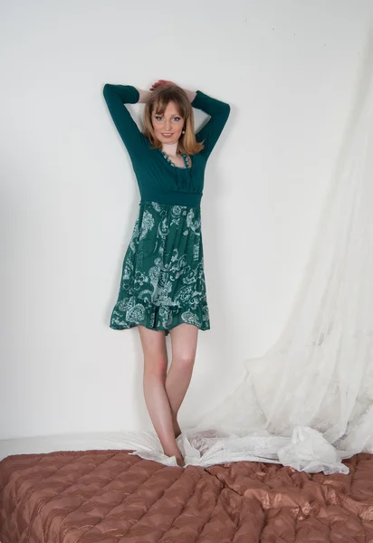 Sexig kvinna i grön klänning på sängen — Stockfoto