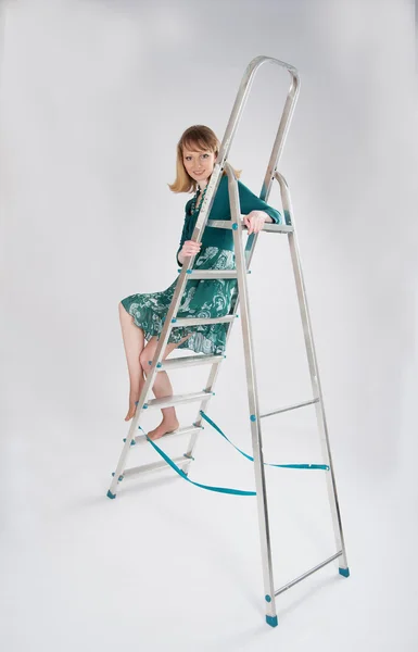 Frau in grünem Kleid sitzt auf einer Leiter — Stockfoto