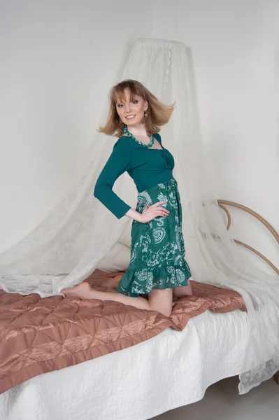 ผู้หญิงเซ็กซี่ในชุดสีเขียวบนเตียง — ภาพถ่ายสต็อก