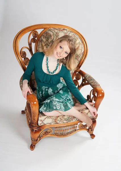 L Frau in grünem Kleid sitzt auf einem Stuhl — Stockfoto