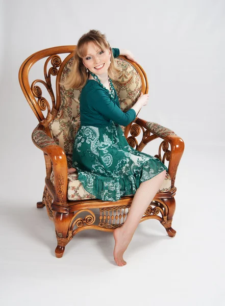 L woman in a green dress sitting on a chair — Stock Photo, Image