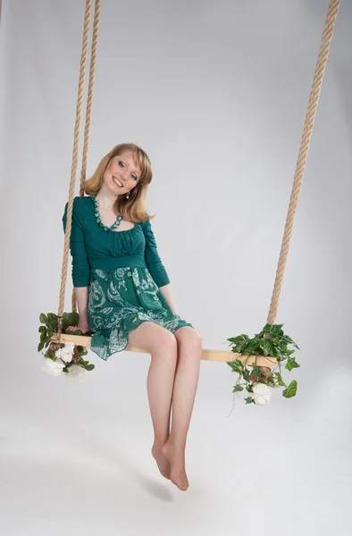 Beautiful woman in a green dress on a swing — Stock Photo, Image