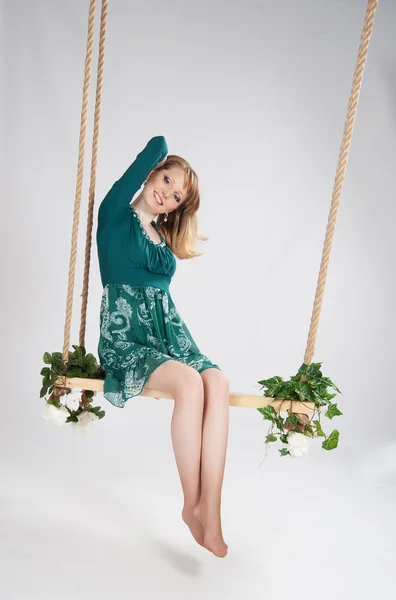 Mooie vrouw in een groene jurk op een schommel — Stockfoto