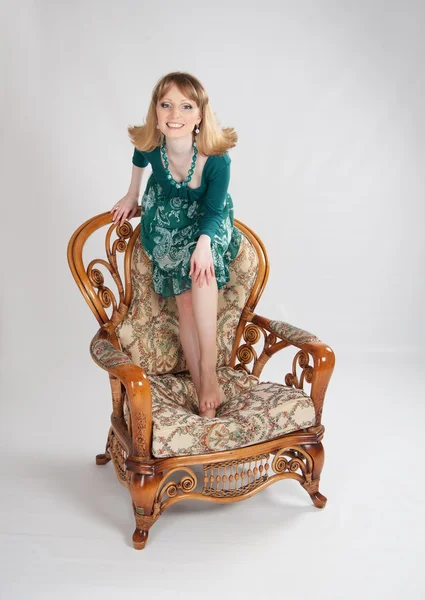 L woman in a green dress sitting on a chair — Stock Photo, Image