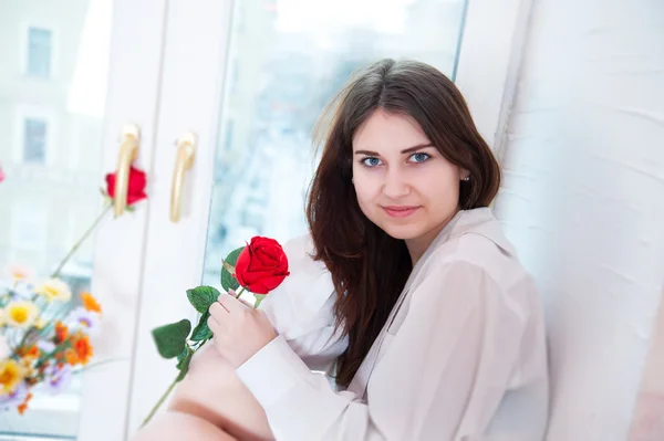 Femme sur un rebord de fenêtre avec une rose — Photo