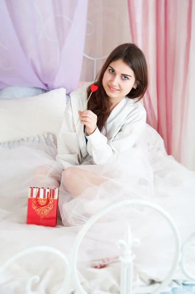 Woman in bed opening a gift — Stock Photo, Image