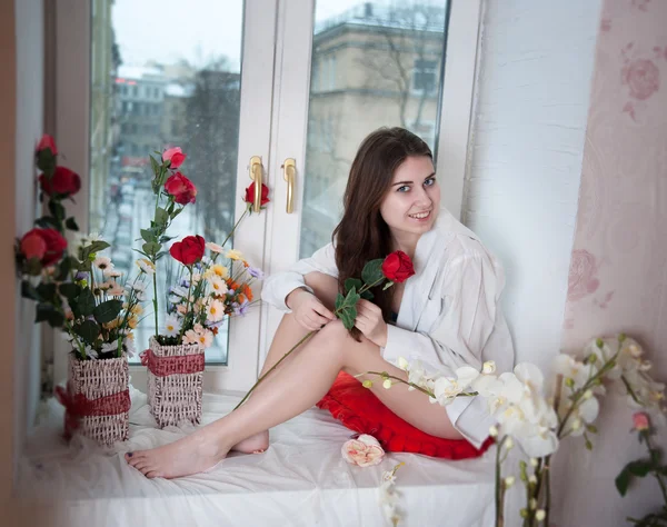 Mulher nas flores no peitoril da janela — Fotografia de Stock