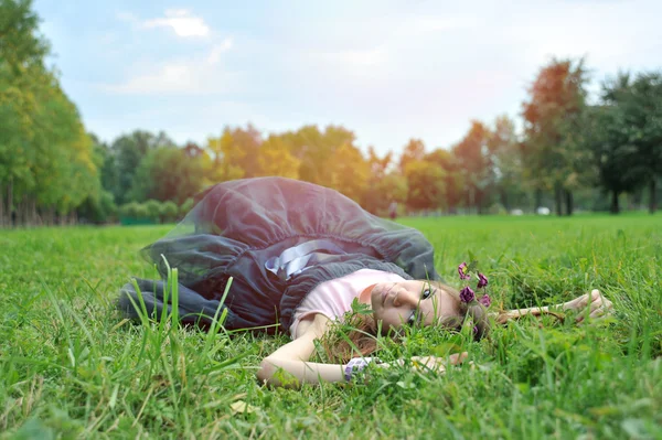 Çimlere yatan bir çelenk ile genç kız — Stok fotoğraf