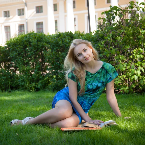 Chica está acostada en la hierba con un libro — Foto de Stock