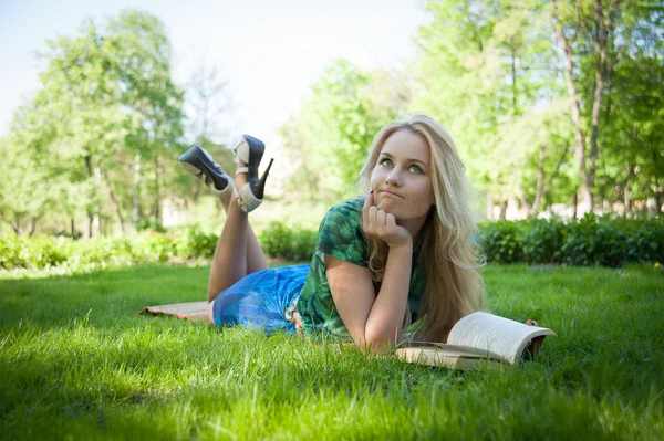 Flicka lägger på gräset med en bok — Stockfoto